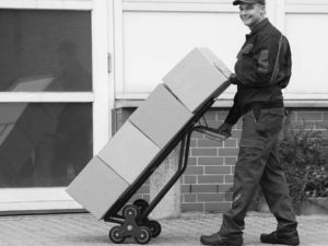 Courier using health and safety approved equipment including a sack truck to deliver boxes
