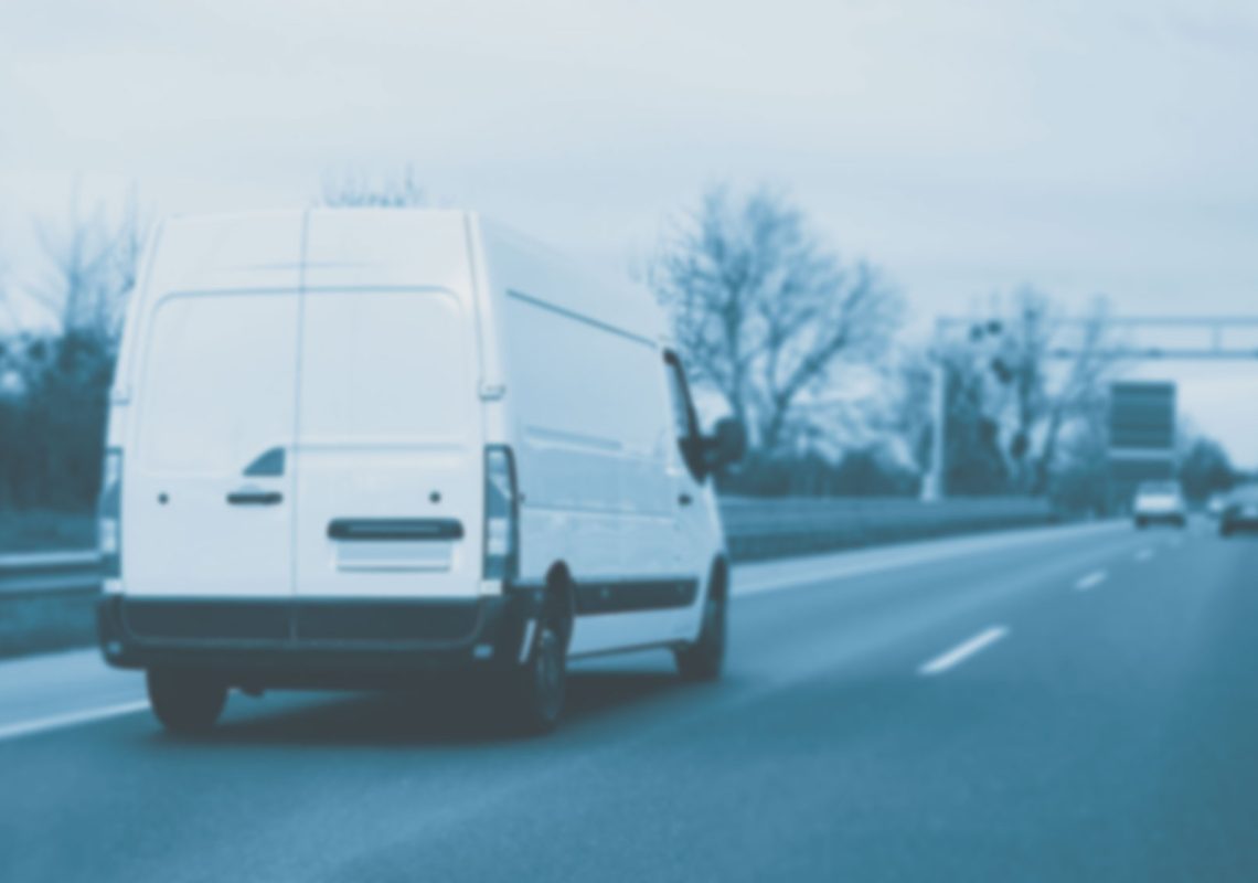 a blurred and de-coloured image of a courier delivery van on a motorway in winter