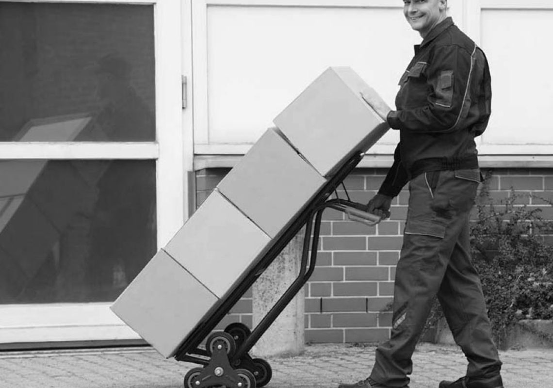 Courier using health and safety approved equipment including a sack truck to deliver boxes