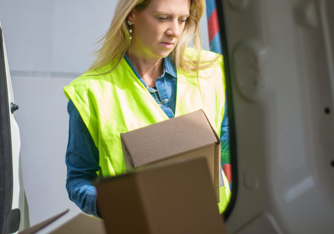 woman delivery driver loading boxes into a van for transporting to customers